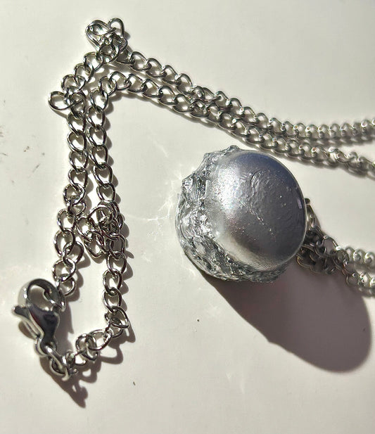 Silver burger shaped necklace on a light background