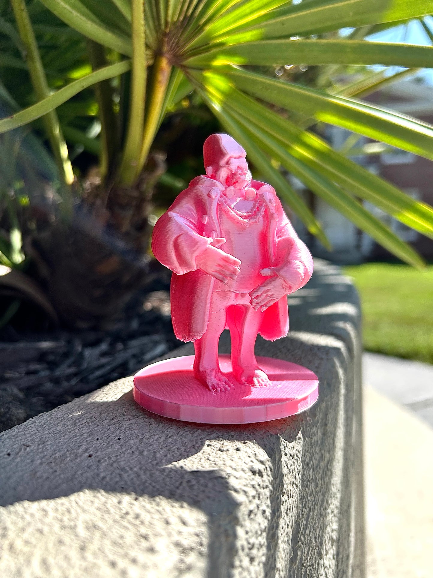 Pink Gorilla figurine on a stone surface with green foliage in the background