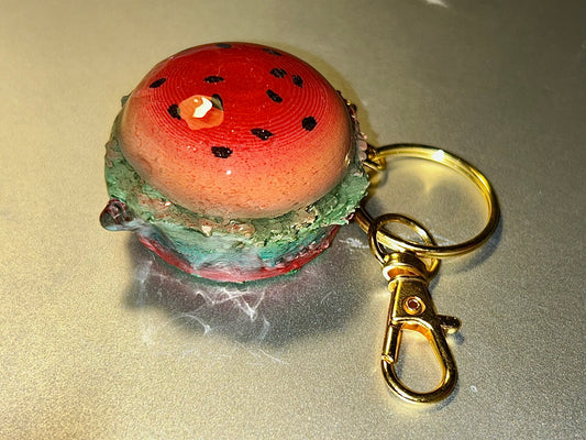Watermelon/strawberry-designed burger keychain on a reflective surface