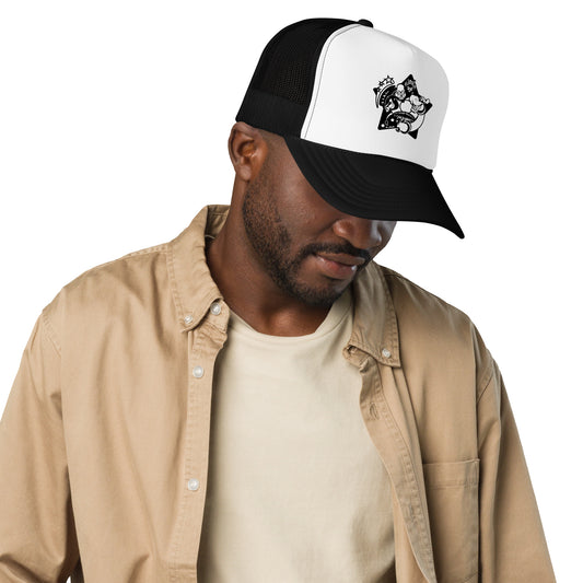 Man wearing a black and white cap with a design, beige jacket, and white shirt on a white background