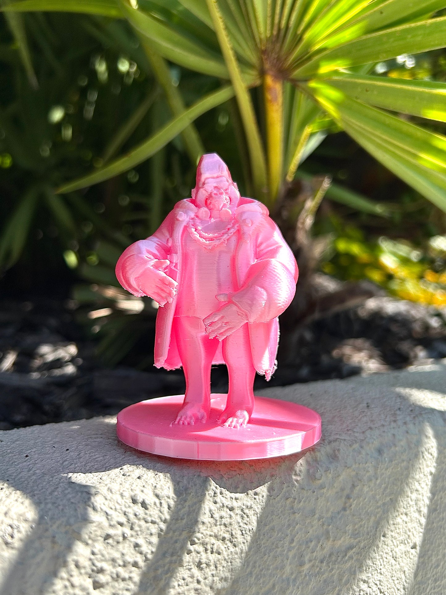 Pink Gorilla figurine on a stone surface with green foliage in the background