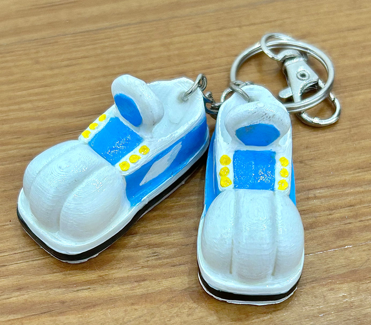 Keychain shaped like cartoon shoes with blue and white design on a wooden background