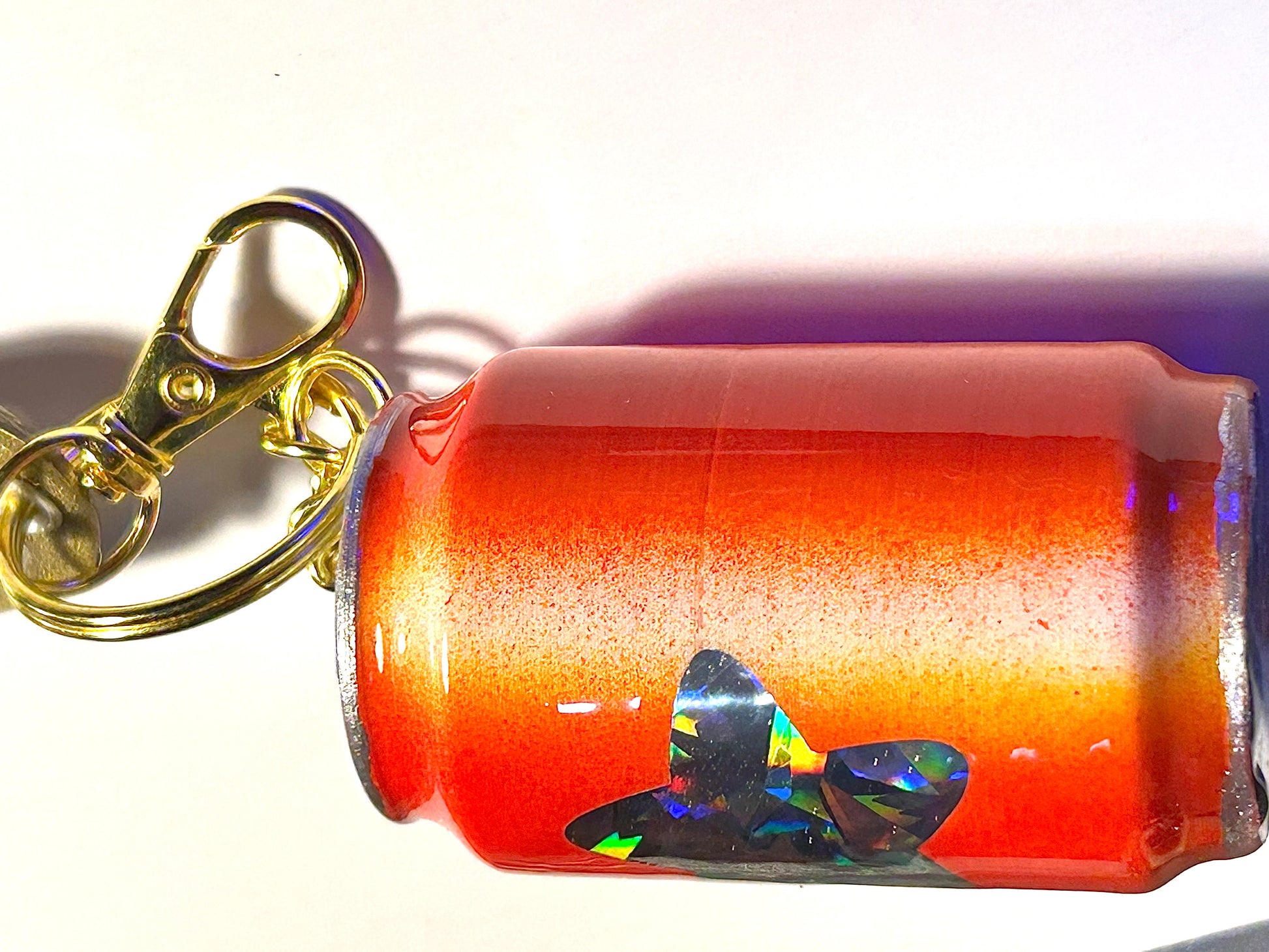 Keychain with a can-shaped soda and soda tab on a white background