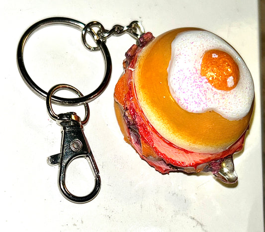 Keychain shaped like a breakfast burger with a bun, meat, and egg on a white background