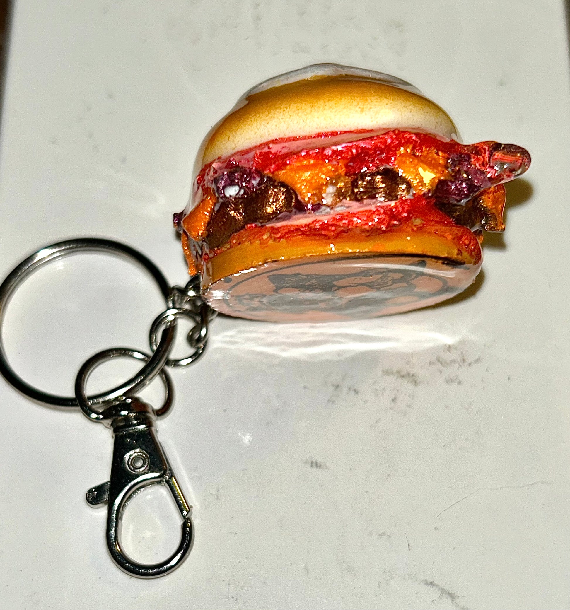 Keychain shaped like a breakfast burger with a bun, meat, and egg on a white background