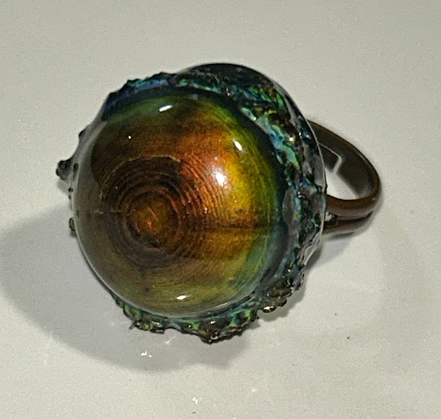 Bronze mood ring with a shiny, reflective surface on a white background