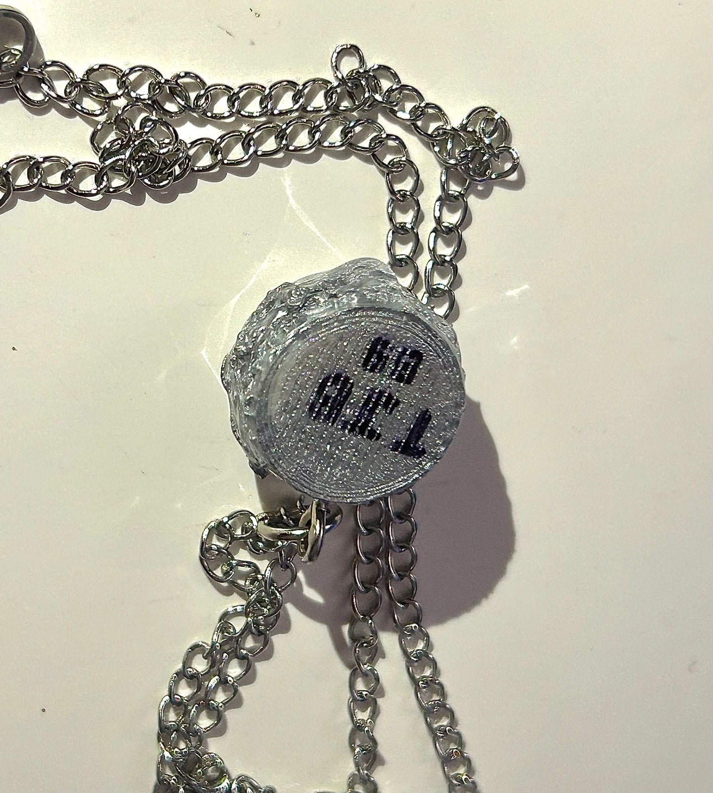 Silver burger shaped necklace on a light background