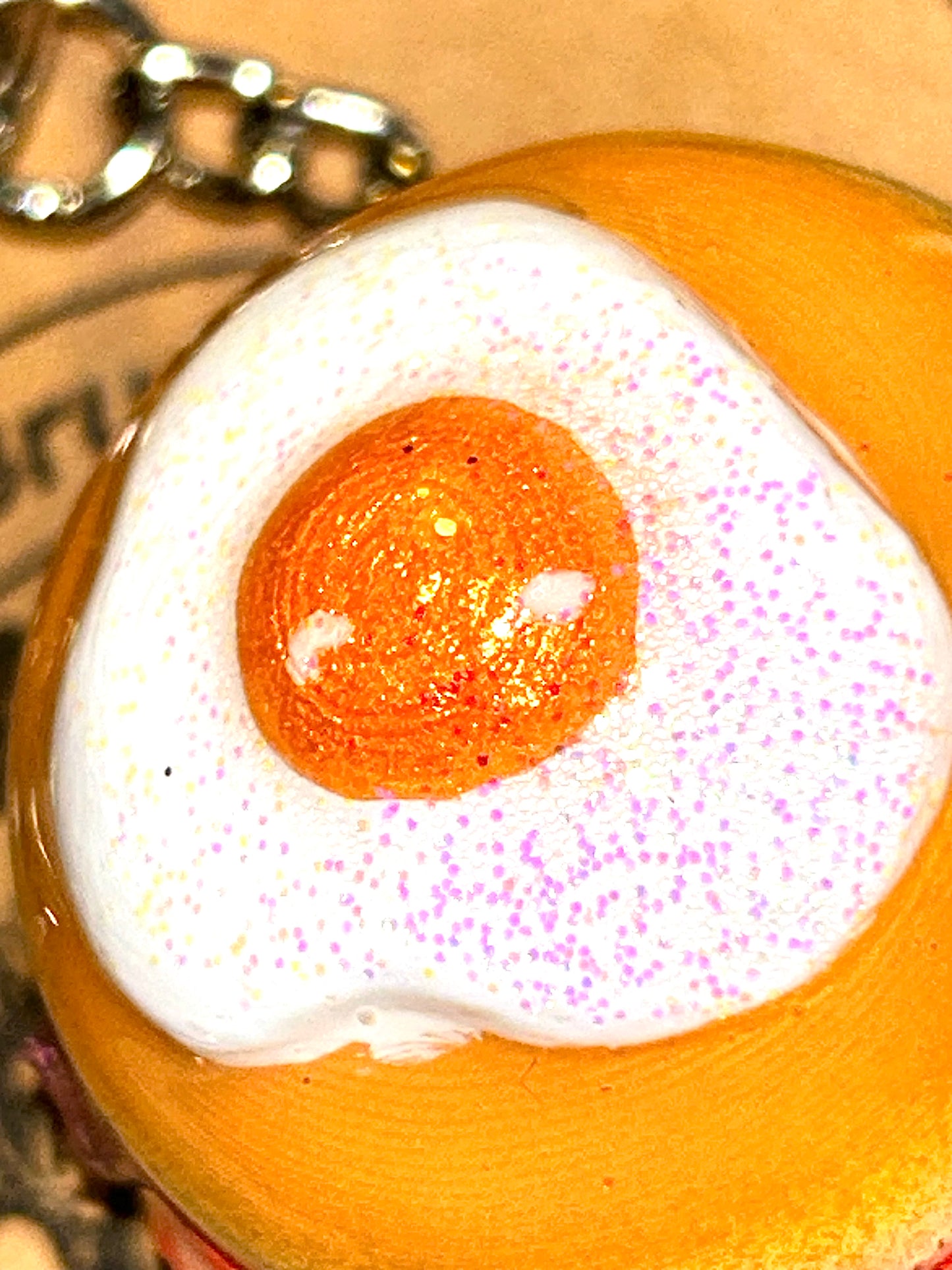 Keychain with a design resembling a fried egg on a cardboard background