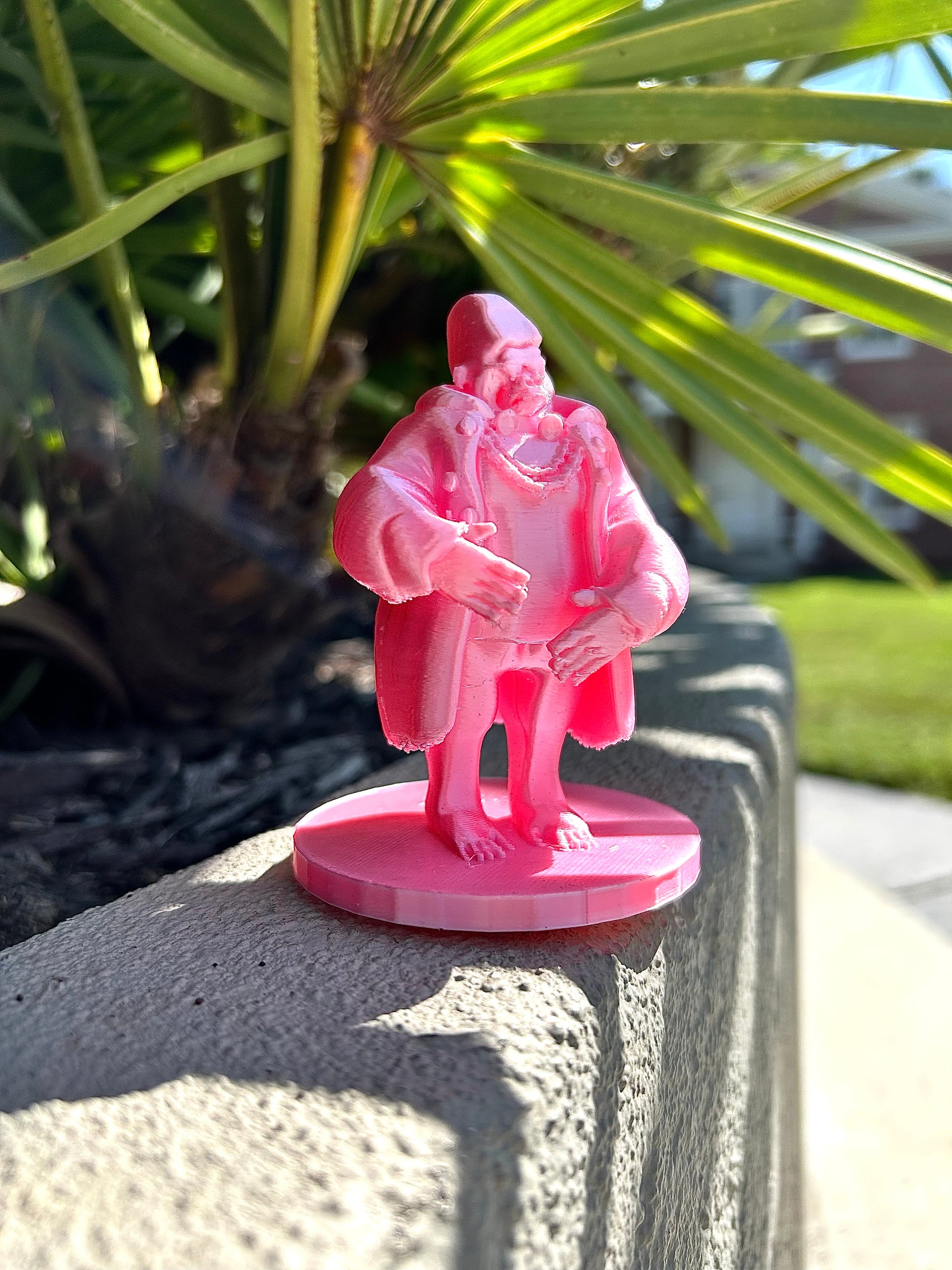 Pink Gorilla figurine on a stone surface with green foliage in the background
