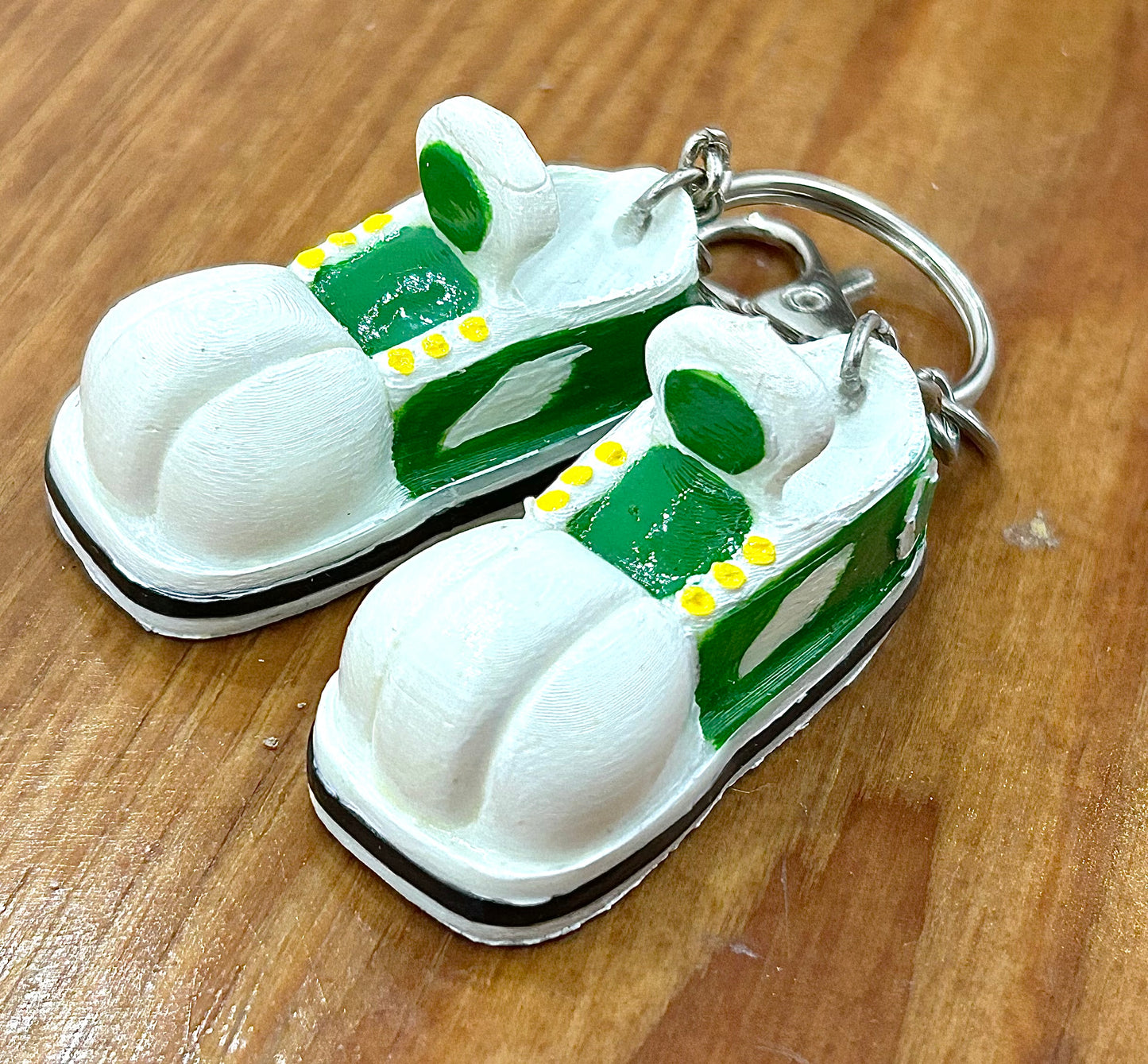 Keychain shaped like cartoon shoes with green and white design on a wooden background