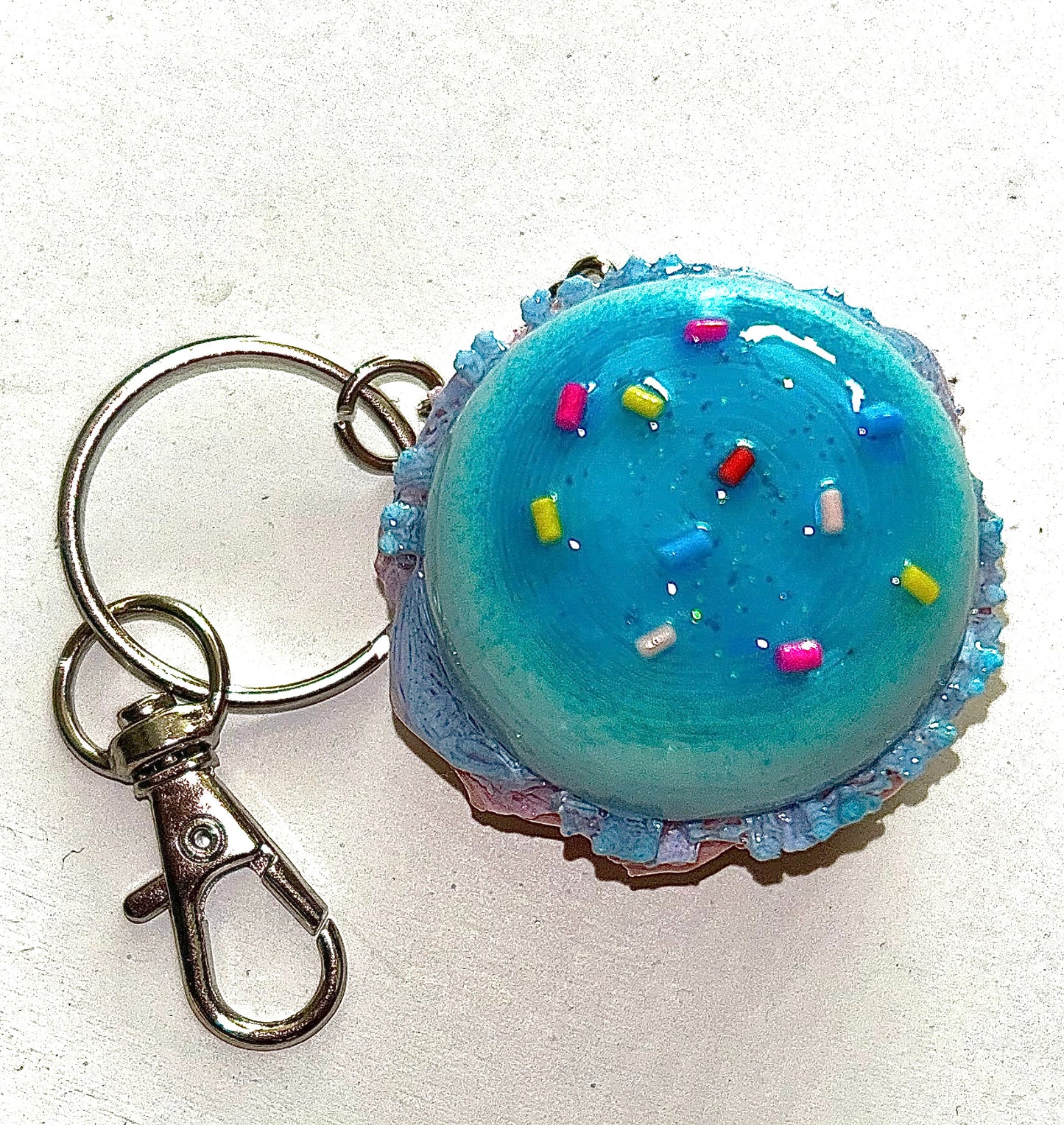 Burger Keychain shaped like a colorful cupcake with blue frosting and sprinkles on a white background