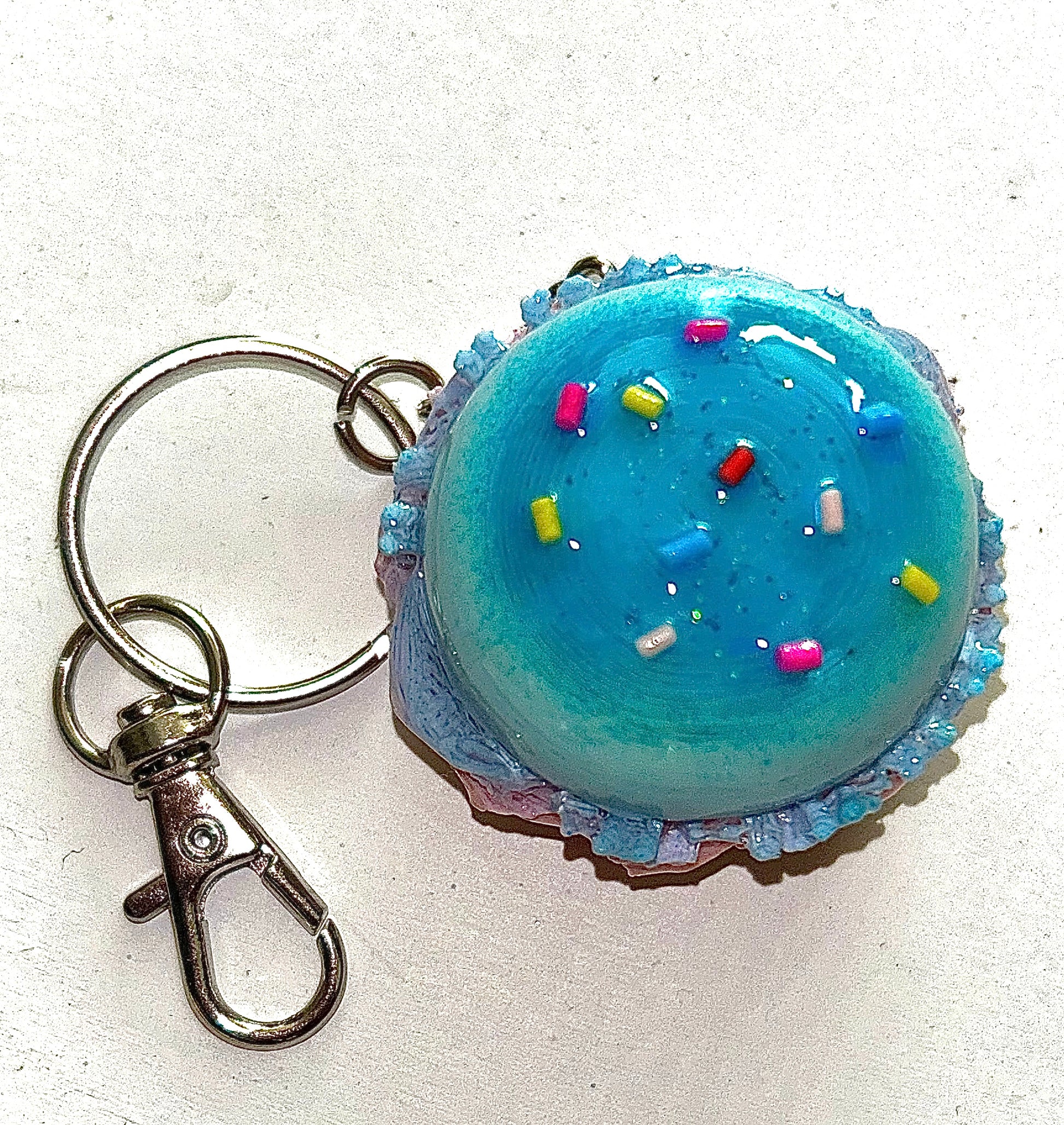 Burger Keychain shaped like a colorful cupcake with blue frosting and sprinkles on a white background